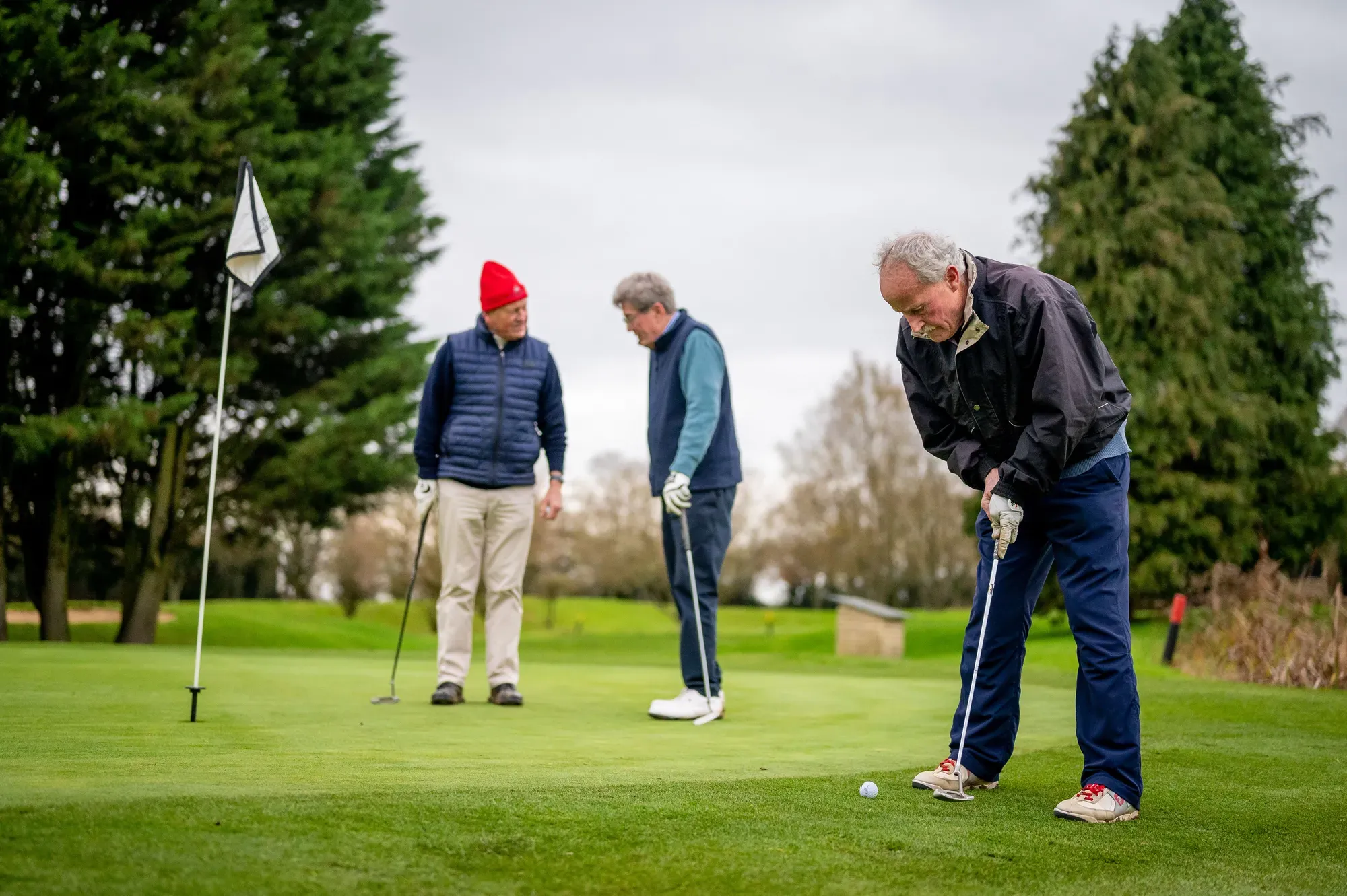 Three golfers on a putting green