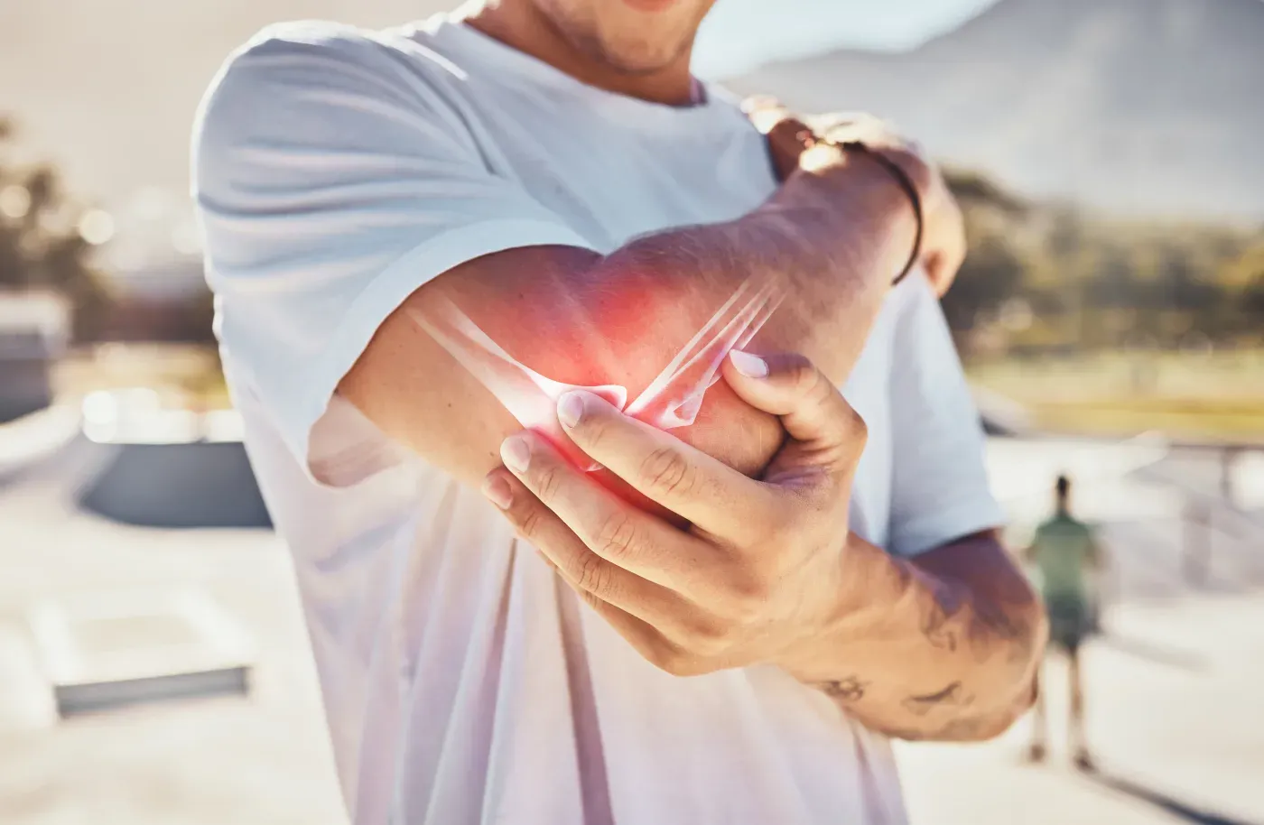 A man holding his forearm, the elbow marked with a red glow