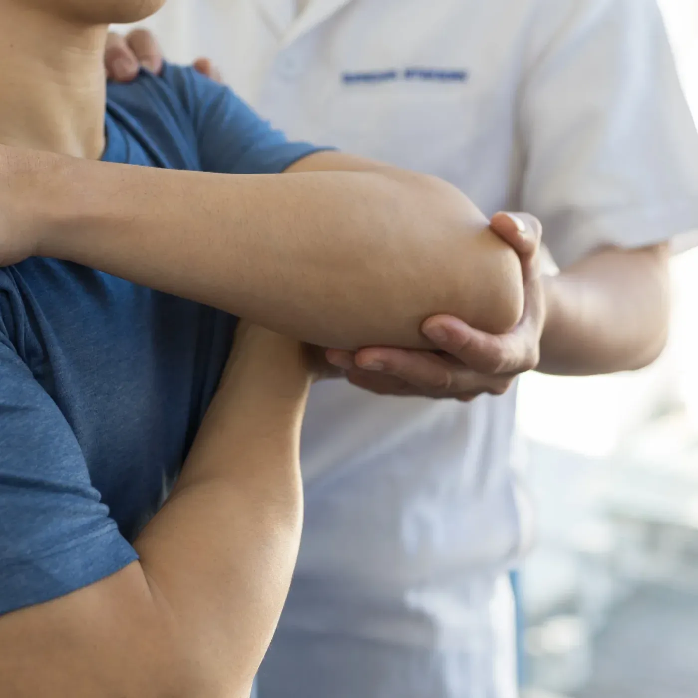 A clinician’s hands supporting a patient’s elbow during an exam