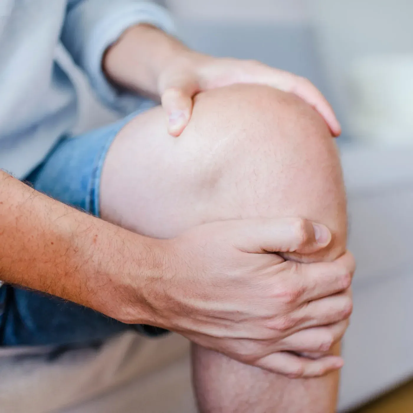 Close view of both hands gripping a bare knee