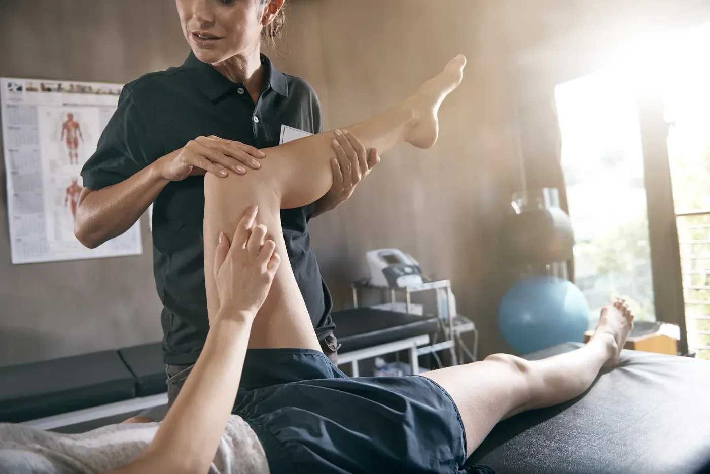 A clinician bending a patient’s knee during an examination