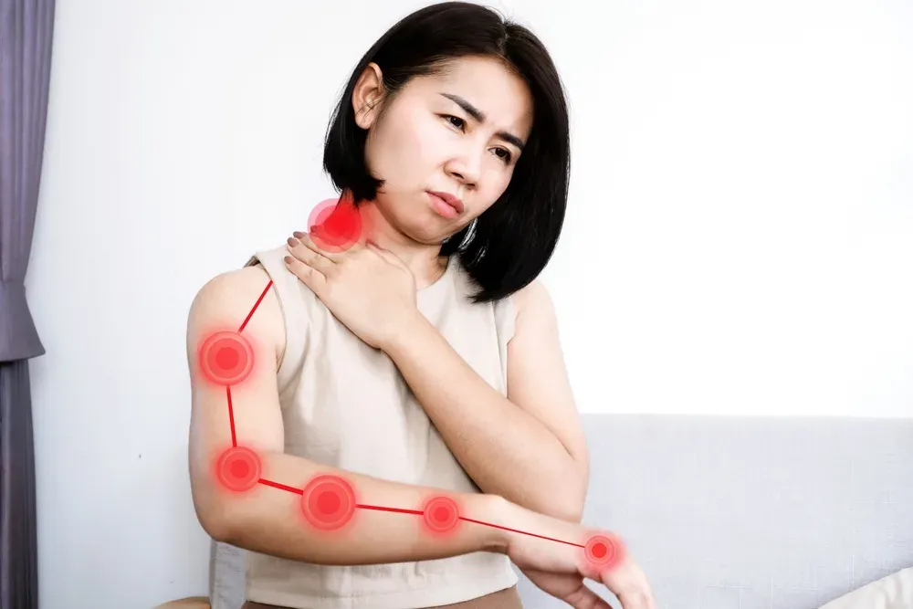 A woman holding her arm, with red markers along the shoulder and arm