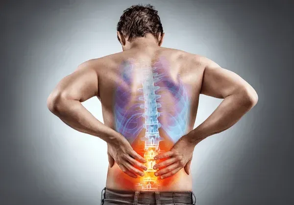 A man holding his lower back, the spine highlighted in red