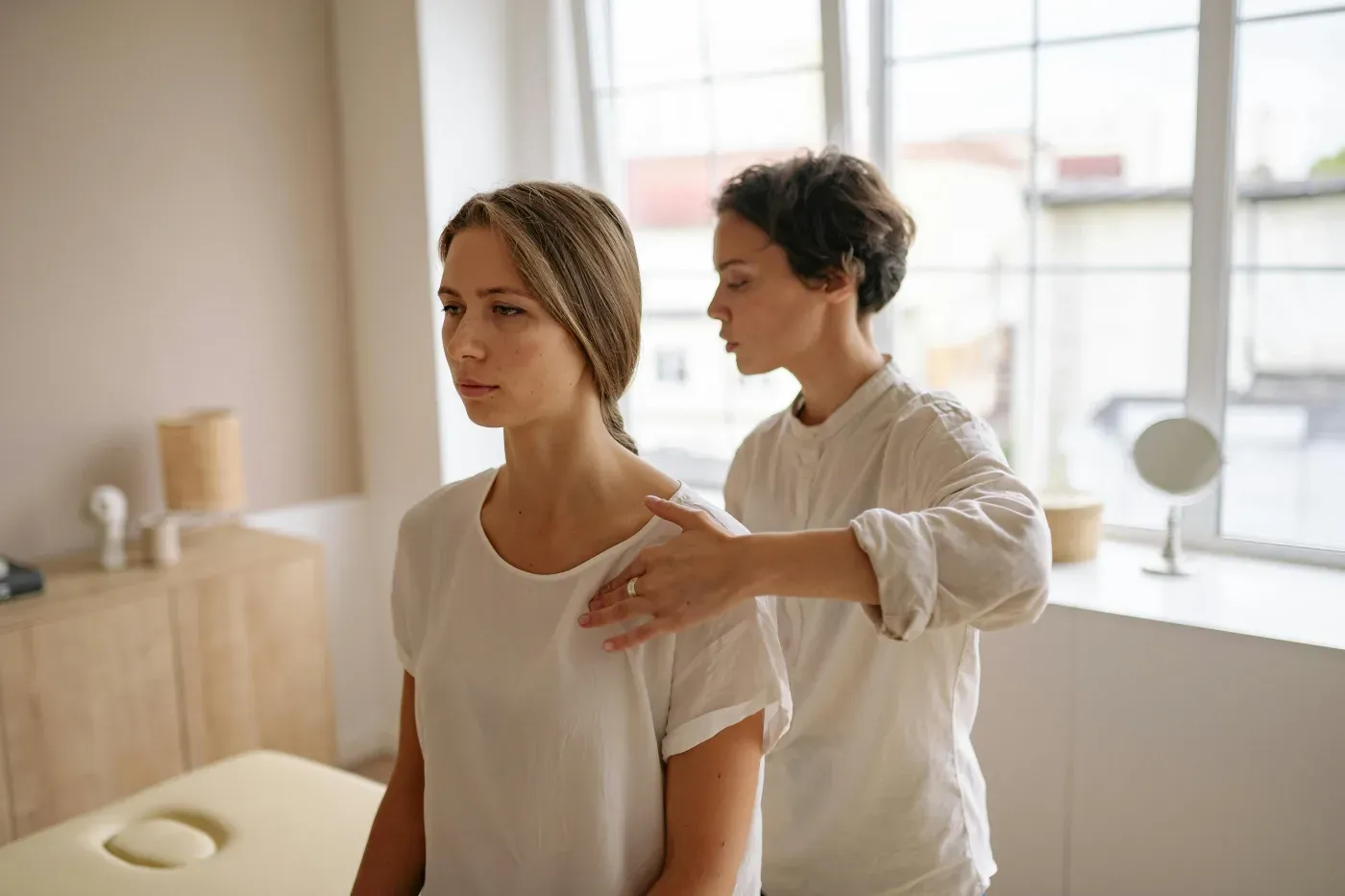 A clinician examining a patient’s shoulder from behind