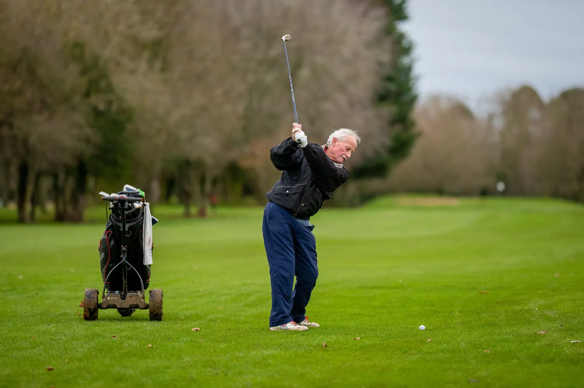 A golfer at the top of a swing on the fairway